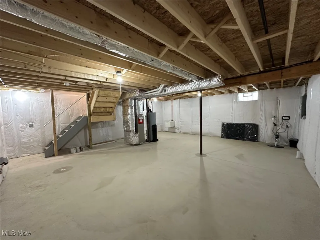 Below grade area with stairway, drainage system, heating unit, and water heater