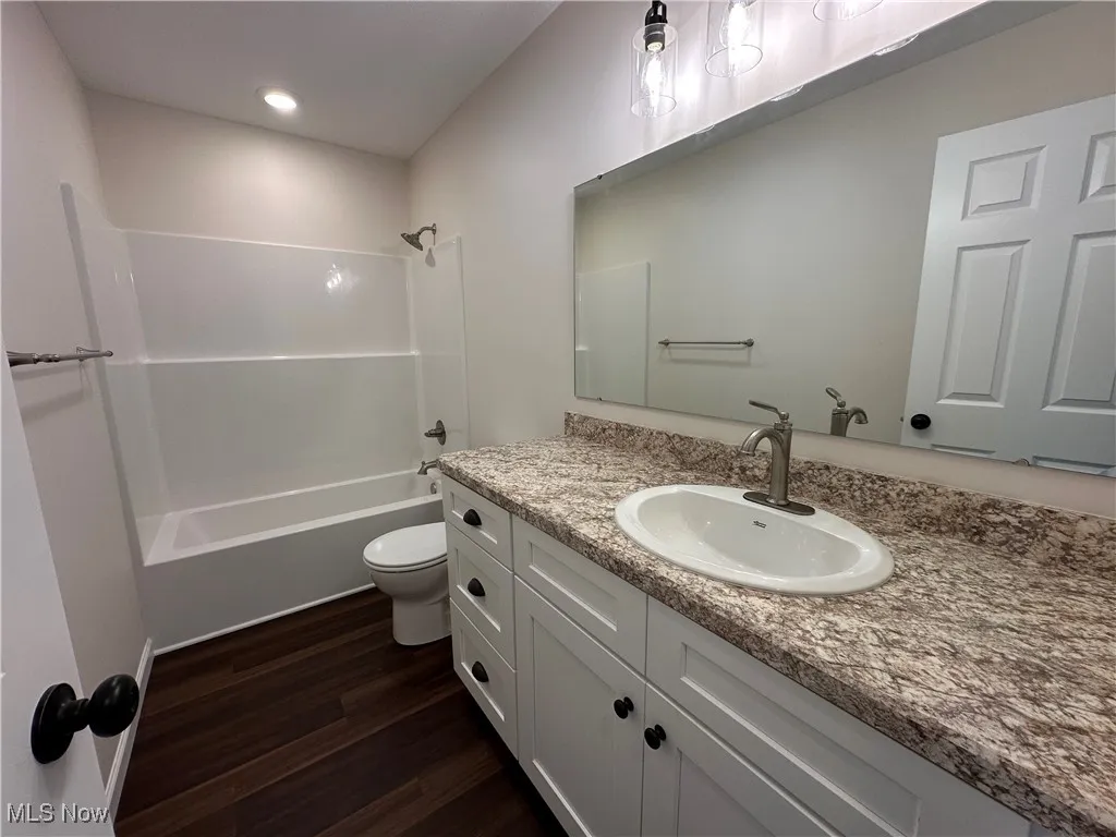 Bathroom with dark wood-style floors, shower / bathtub combination, vanity, and recessed lighting