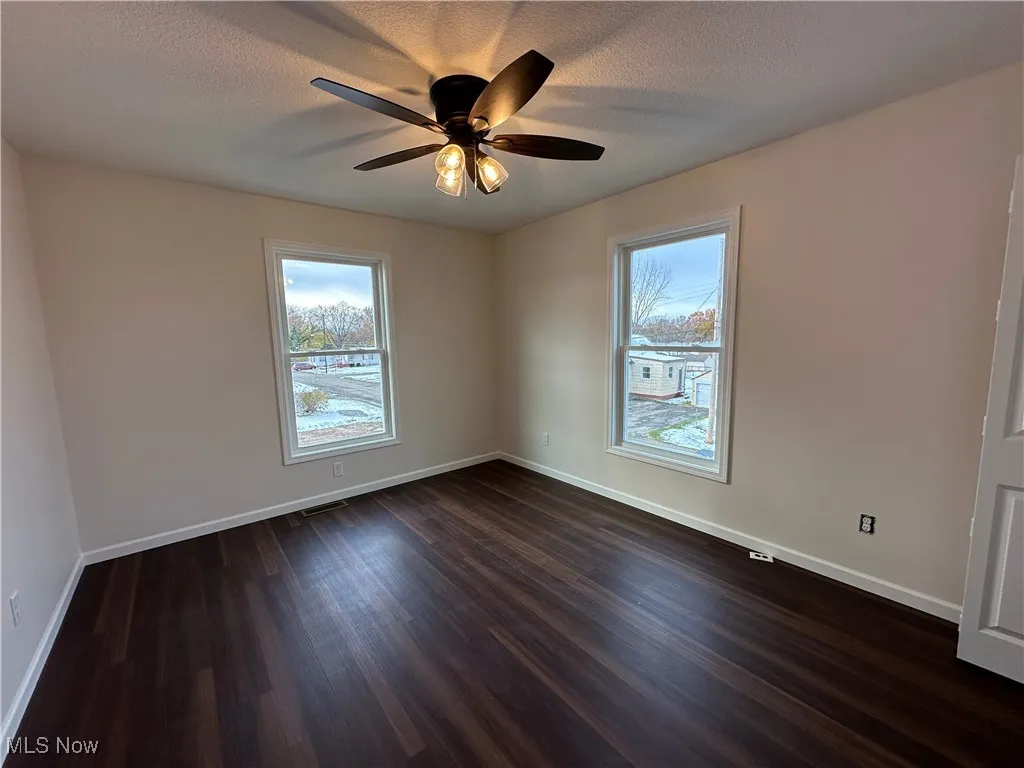 Bedroom with dark wood-type flooring, plenty of natural light, a textured ceiling, and ceiling fan