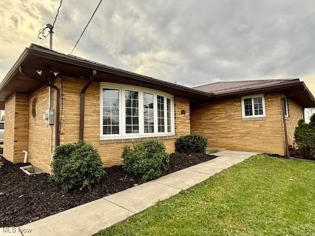 View of side of home with brick siding, a yard, and a metal roof