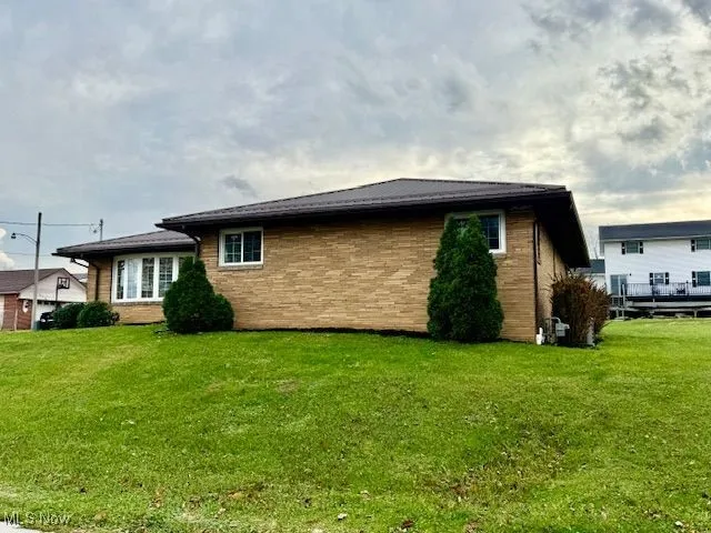 Back of property featuring a lawn, brick siding, and a deck