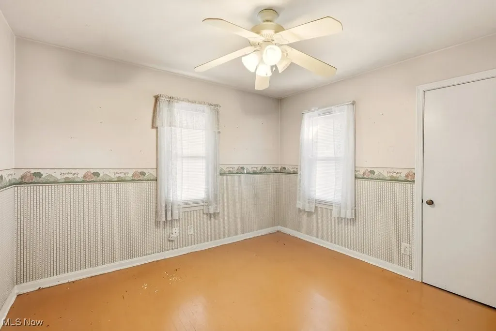 Empty room with a wainscoted wall and ceiling fan