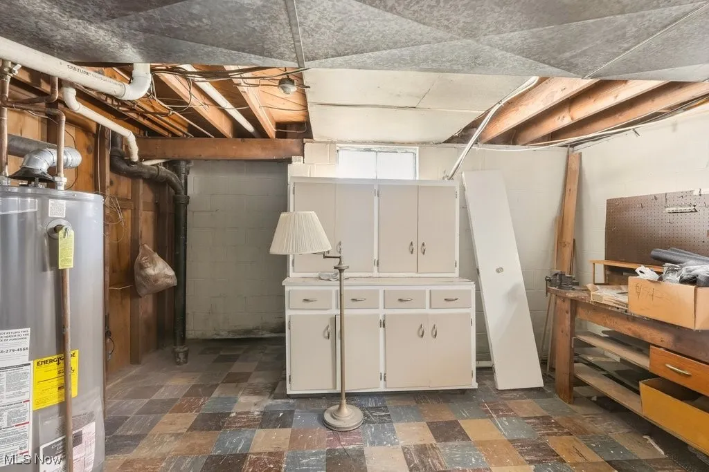 Unfinished below grade area with dark flooring and gas water heater