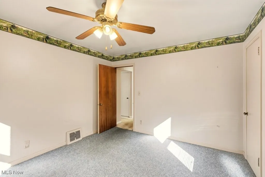 Carpeted spare room with baseboards and a ceiling fan