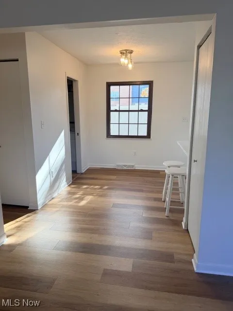 Unfurnished dining area featuring baseboards and dark wood-style floors