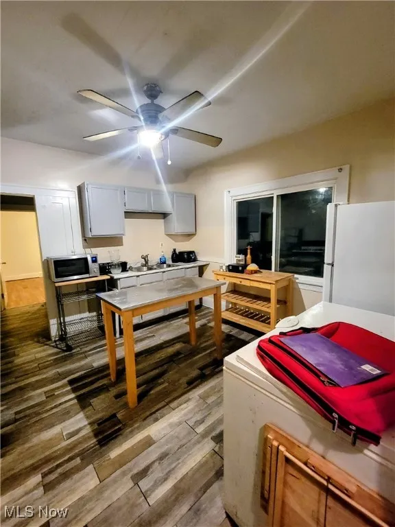 Kitchen with freestanding refrigerator, light wood-type flooring, gray cabinets, stainless steel microwave, and light countertops