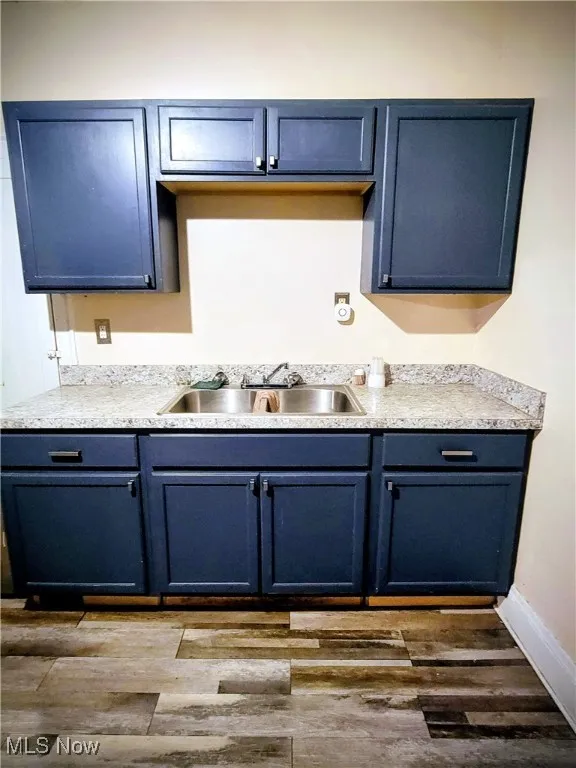 Kitchen featuring blue cabinets, light countertops, and dark wood finished floors