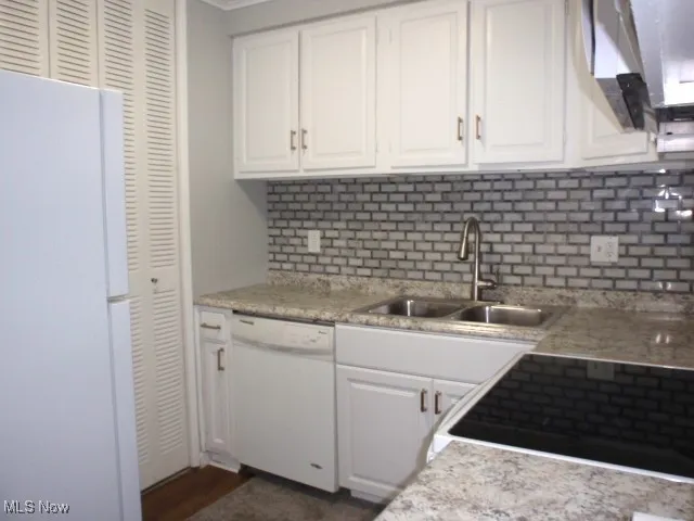 Kitchen with white cabinets, white appliances, and backsplash