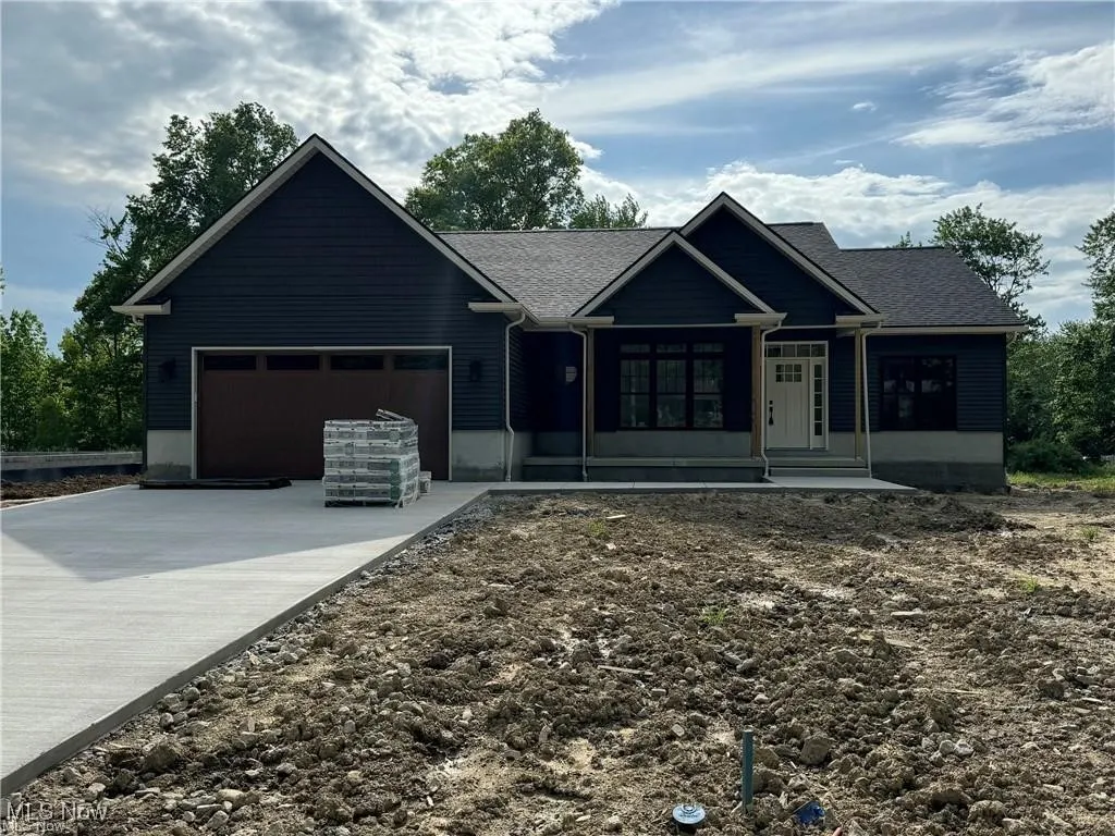 Ranch-style house featuring driveway, an attached garage, and roof with shingles