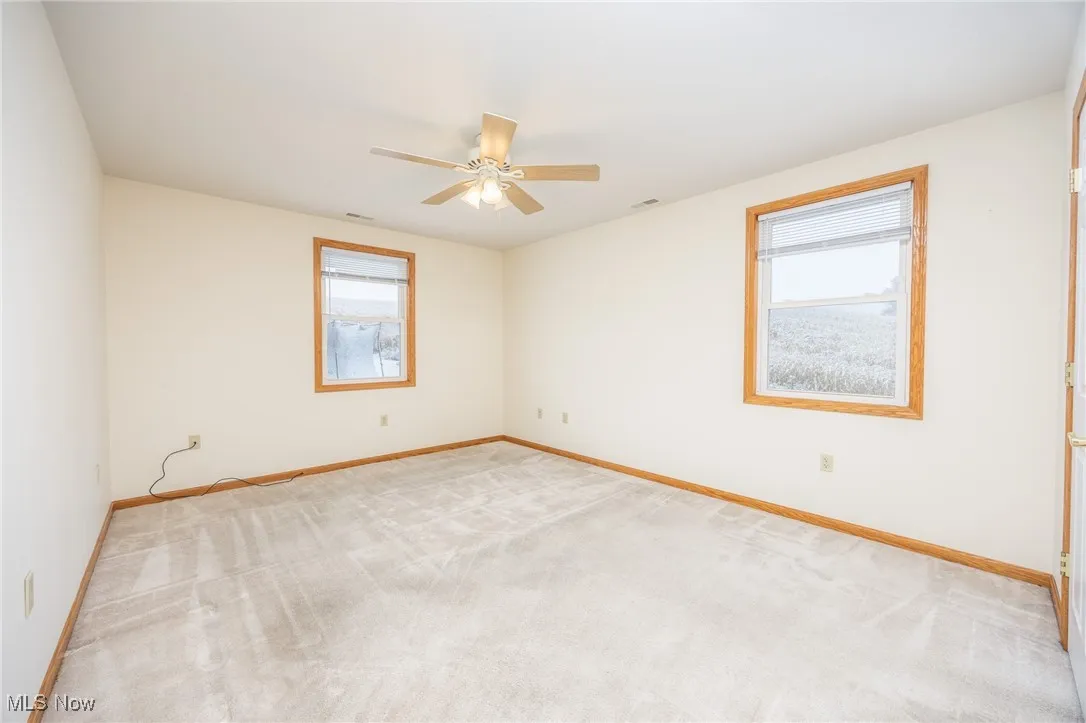 Empty room featuring light colored carpet and baseboards