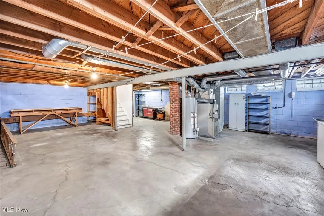 Unfinished basement featuring stairway, heating unit, and gas water heater