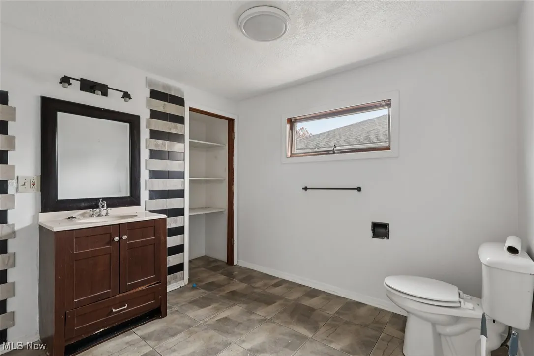 Full bathroom with sink, vanity, commode and tile flooring
