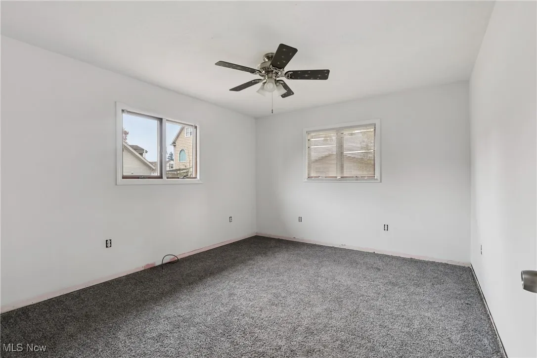 First floor bedroom with carpet flooring and a ceiling fan / light