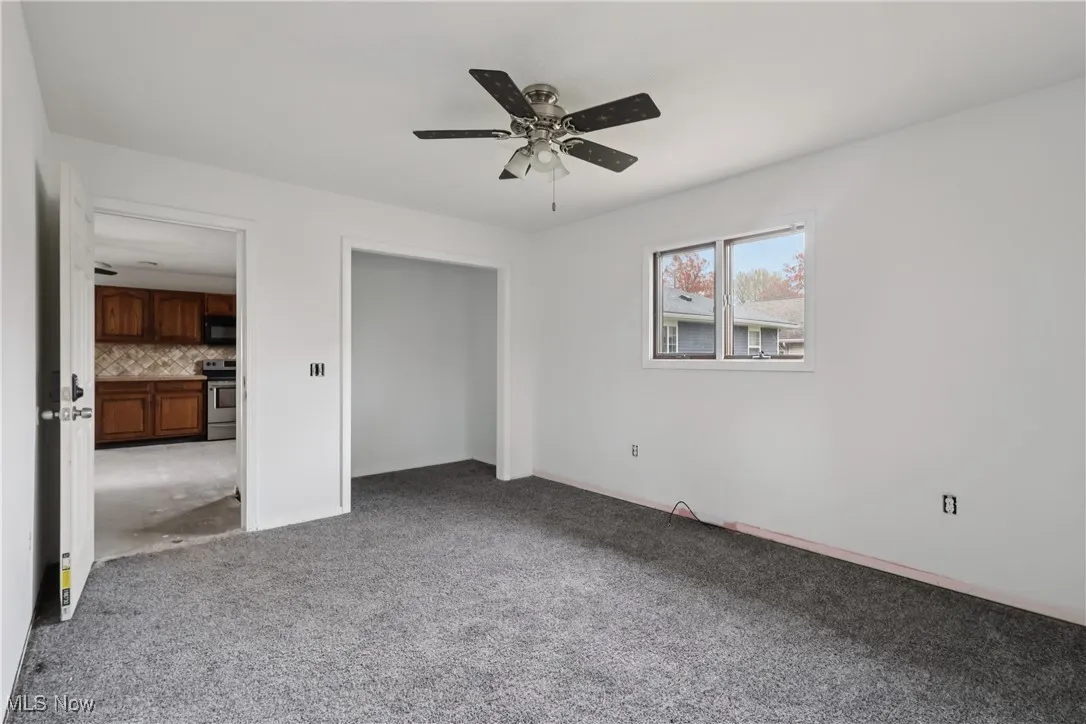 Another view of the first floor bedroom with carpet flooring, closet and ceiling fan / light