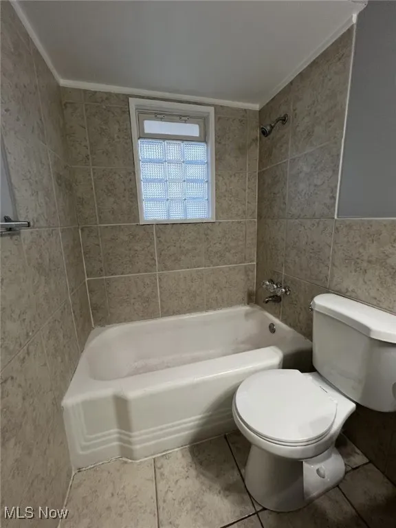 Bathroom with tile walls, shower / washtub combination, tile patterned flooring, and crown molding
