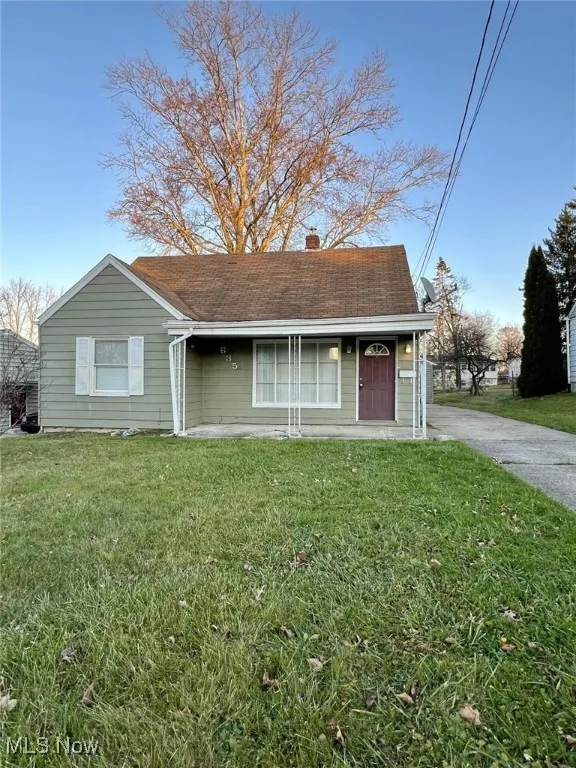 View of front of property featuring a front lawn, a chimney, and roof with shingles