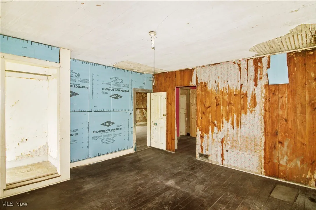 Unfurnished room with wood walls and dark wood-style floors