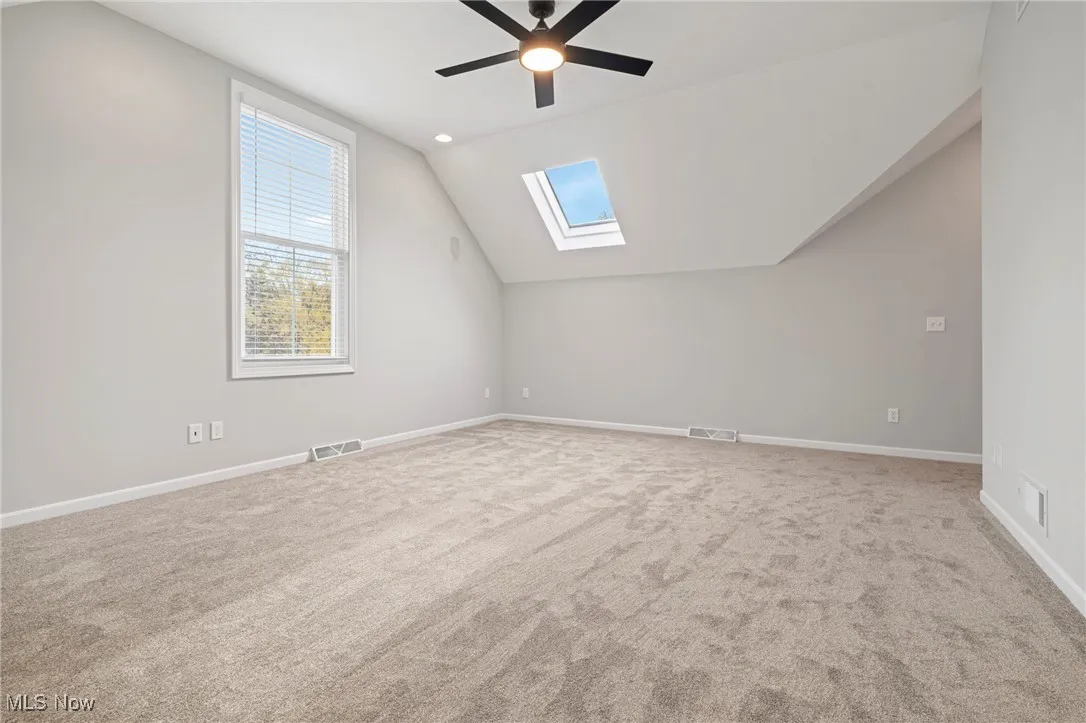 Additional living space featuring lofted ceiling, a skylight, light colored carpet, a ceiling fan, and recessed lighting