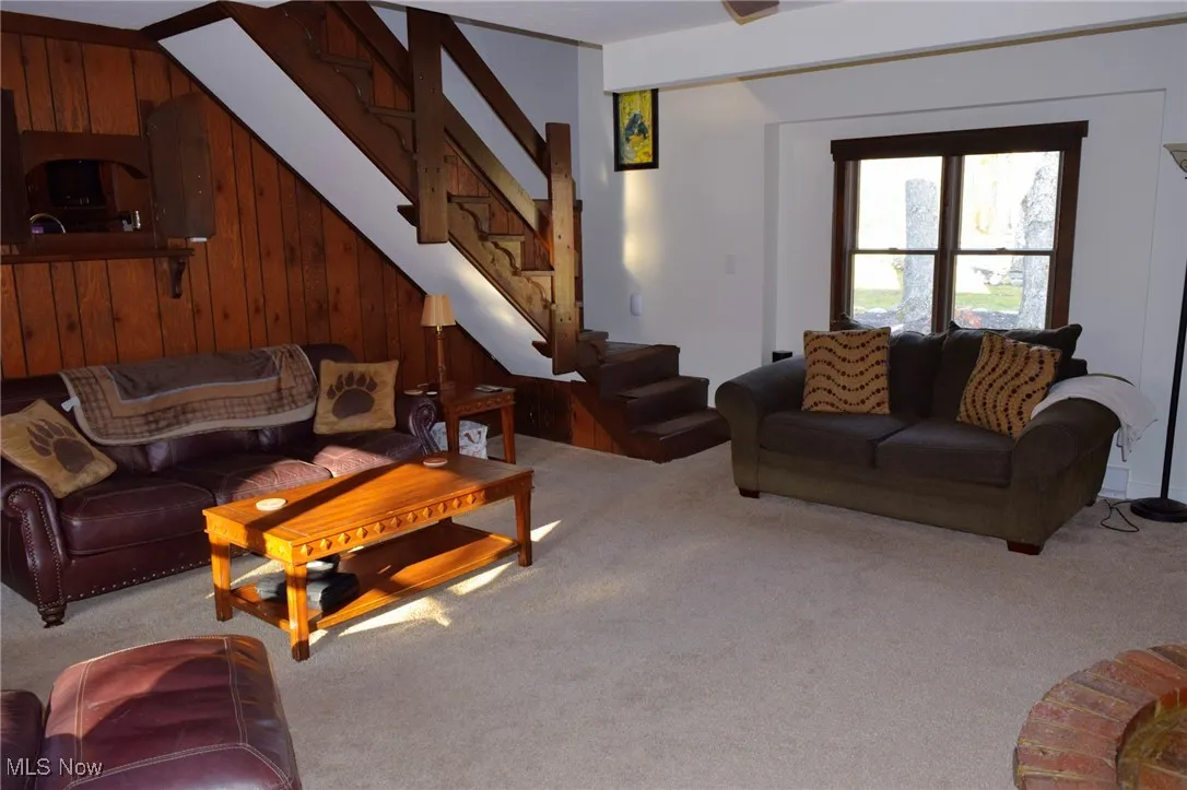 Living area with wood walls, carpet floors, and stairway