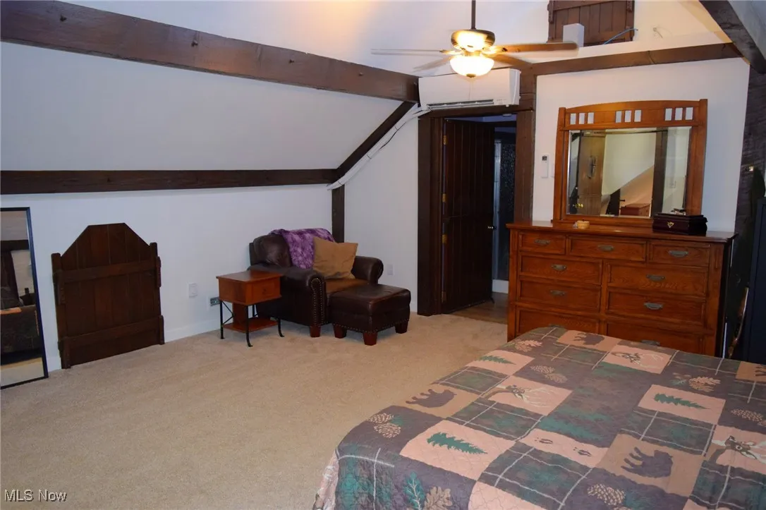 Bedroom featuring light colored carpet, a wall mounted AC, and ceiling fan