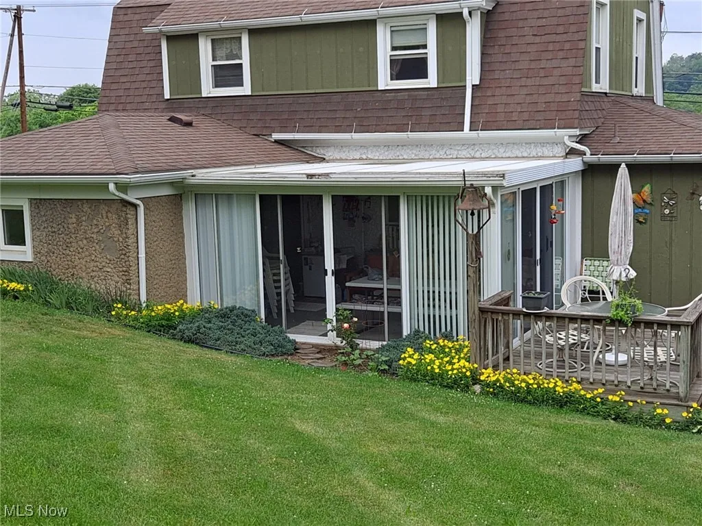 Rear view of property featuring a sunroom and back deck