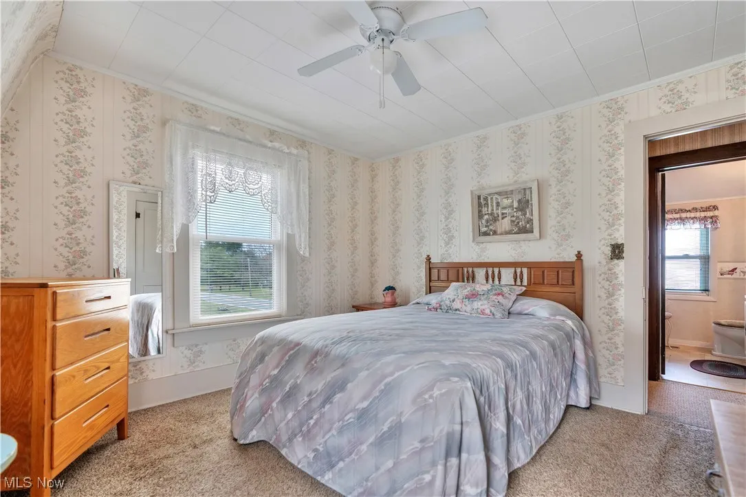 Bedroom #1 featuring light colored carpet, crown molding, and a ceiling fan