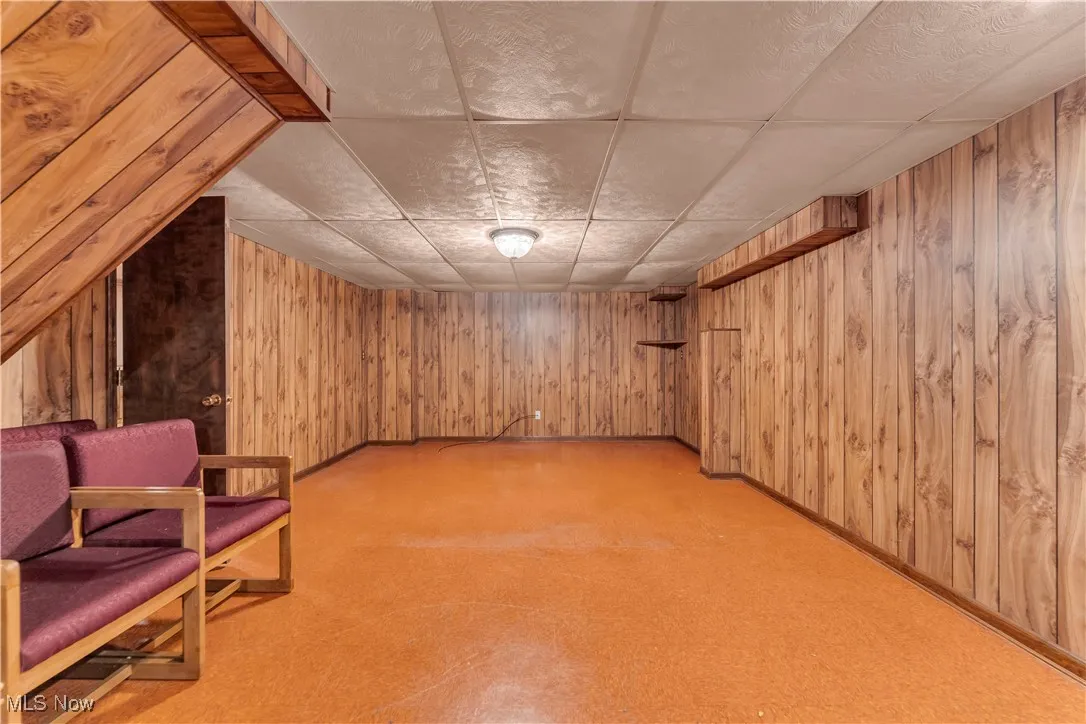 Unfurnished room featuring a paneled ceiling and wood walls