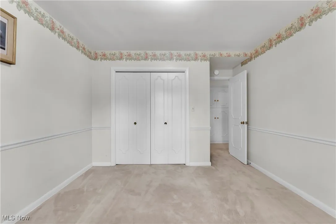 Unfurnished bedroom with light colored carpet and a closet