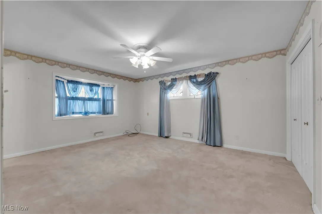 Unfurnished bedroom featuring light carpet, a closet, and a ceiling fan