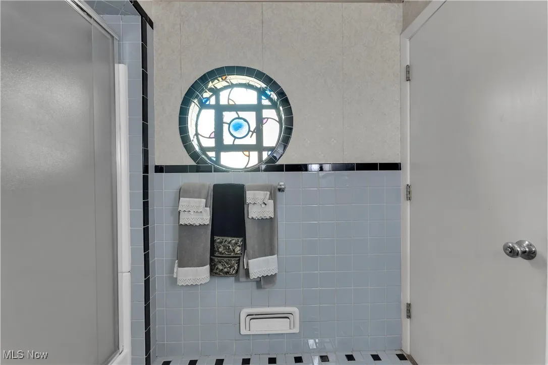 Full bathroom with a shower stall and tile walls