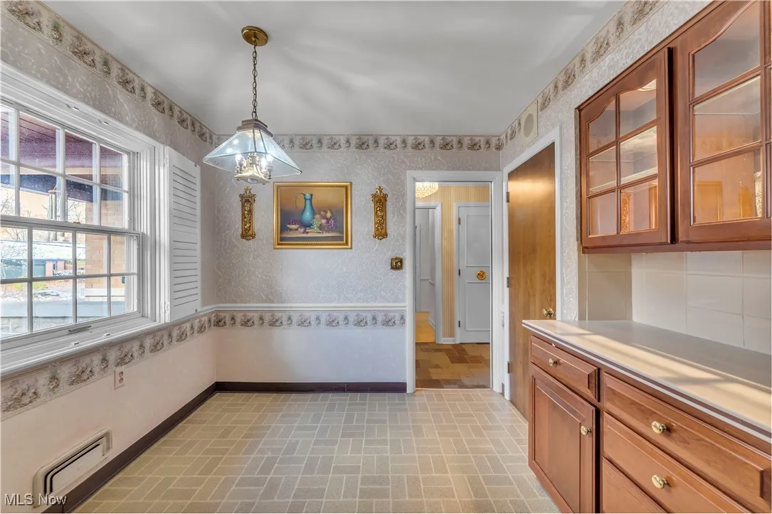 Unfurnished dining area with wallpapered walls, baseboard heating, and brick patterned floors