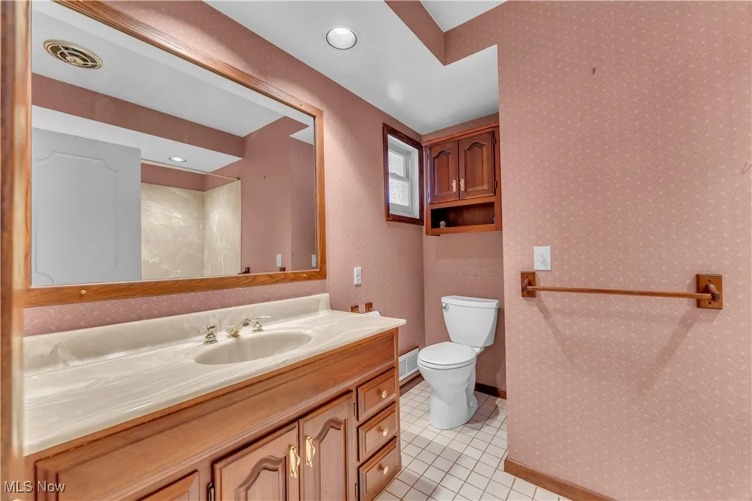Bathroom with vanity, light tile patterned floors, wallpapered walls, and recessed lighting