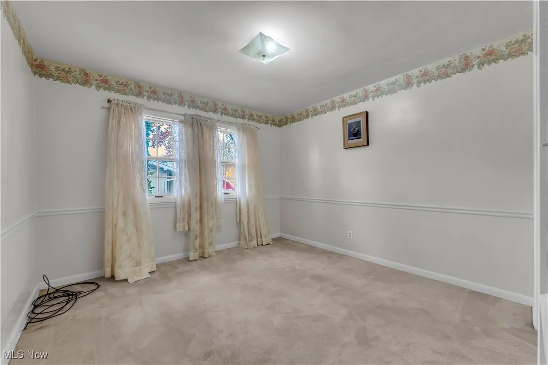 Empty room featuring light colored carpet and baseboards
