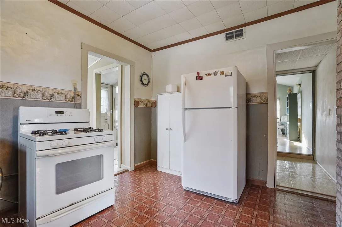 Kitchen featuring white appliances, crown molding, and dark floors