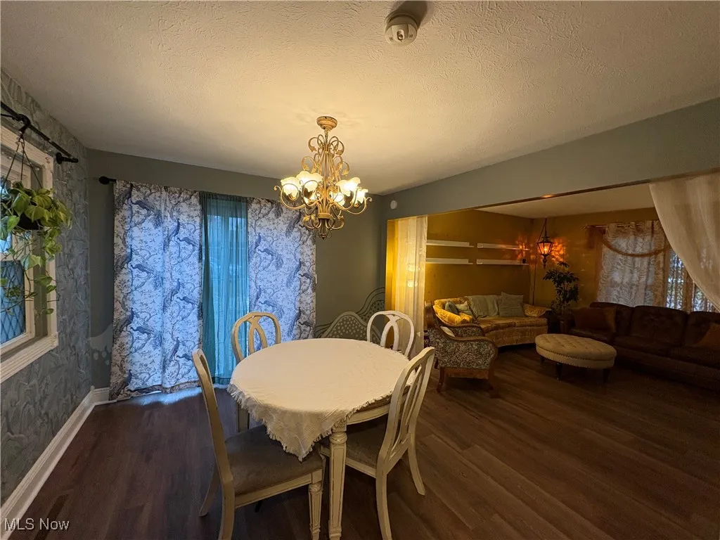 Dining area featuring a textured ceiling, a chandelier, and dark wood-style flooring