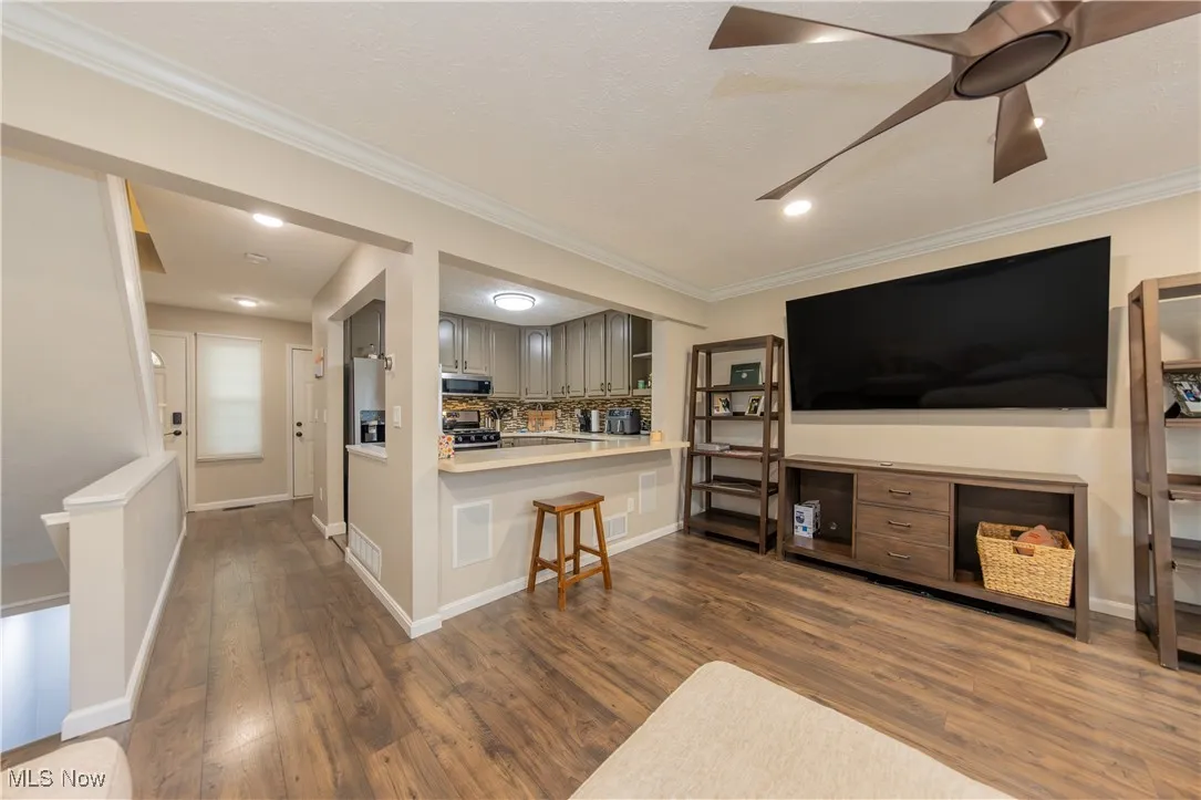 Living room with ornamental molding, dark wood-type flooring, and recessed lighting