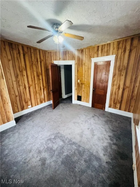 Unfurnished bedroom with carpet, a textured ceiling, and ceiling fan