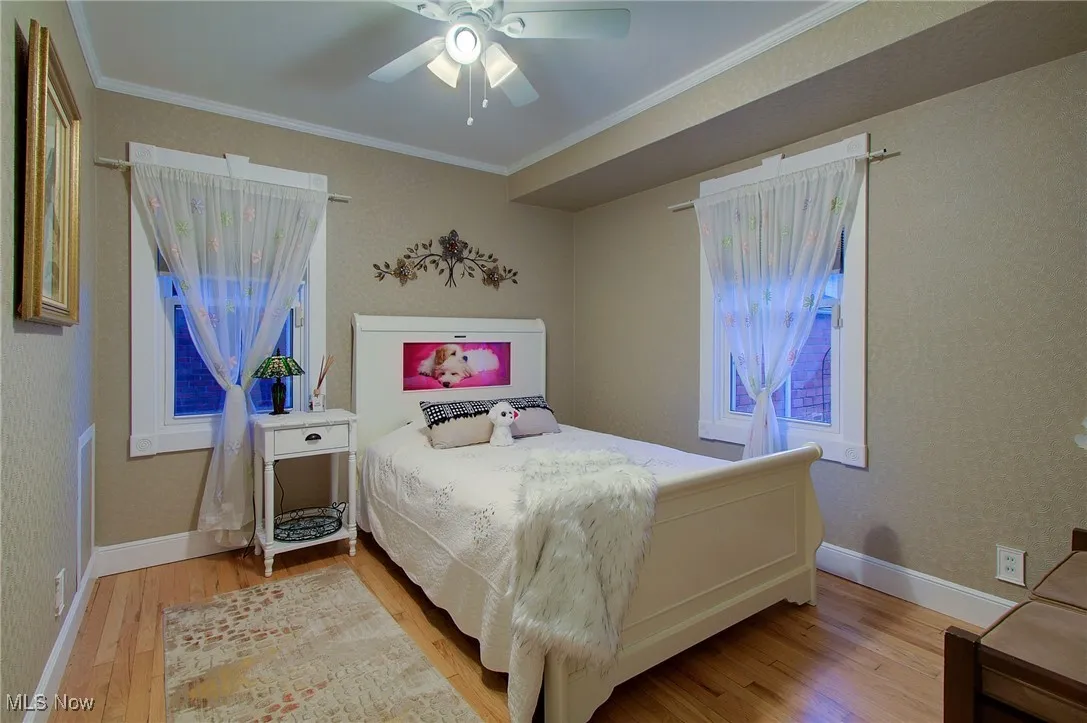 Bedroom featuring crown molding, light wood-style floors, and a ceiling fan