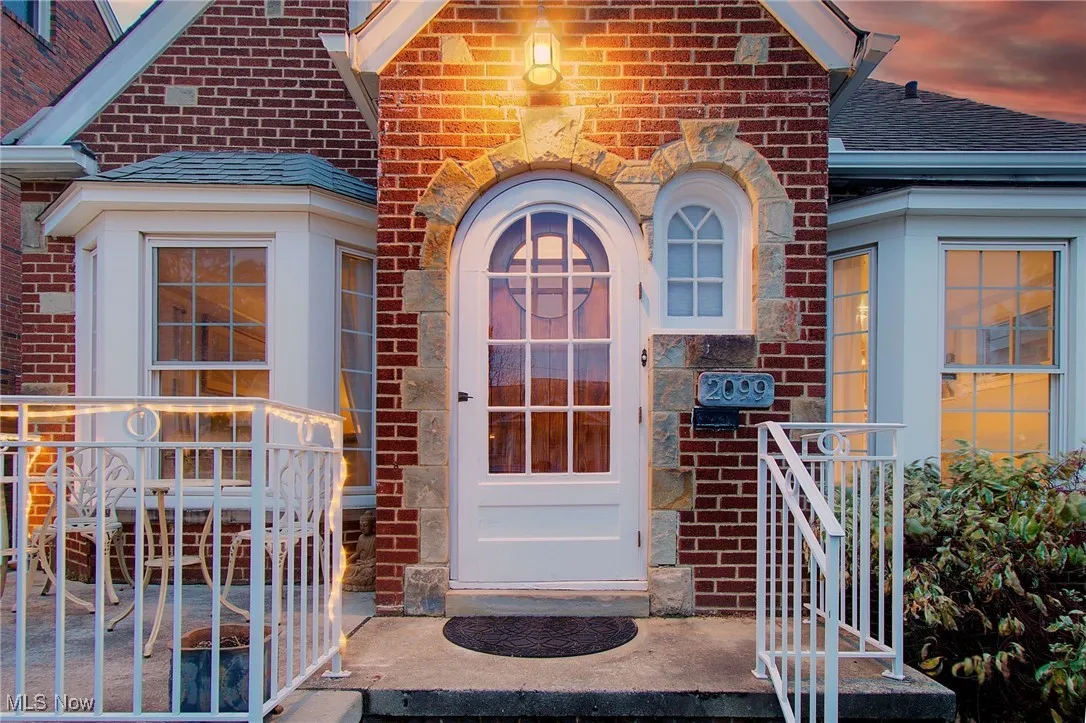 Doorway to property with roof with shingles, brick siding, and stone siding