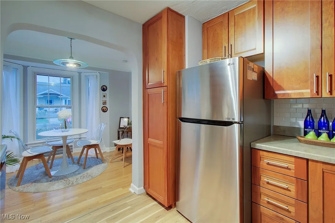 Kitchen with freestanding refrigerator, brown cabinets, light wood-style floors, and backsplash