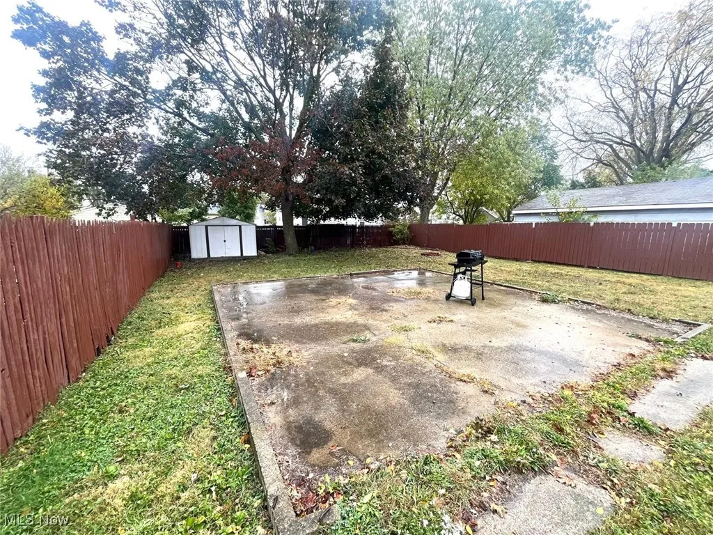 Fenced backyard featuring a patio area and a storage unit