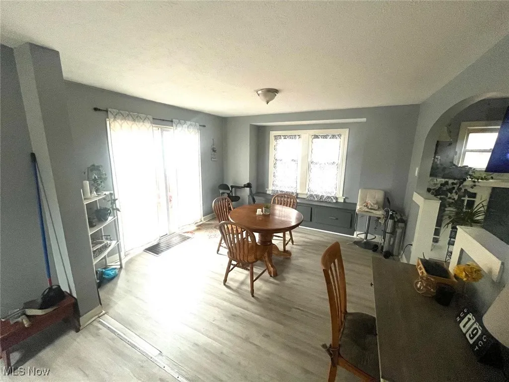 Dining space with arched walkways, light wood-style flooring, healthy amount of natural light, and a textured ceiling