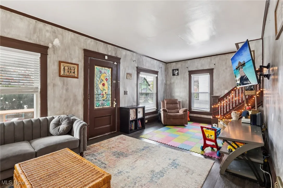 Living room featuring wood finished floors, stairway, and crown molding