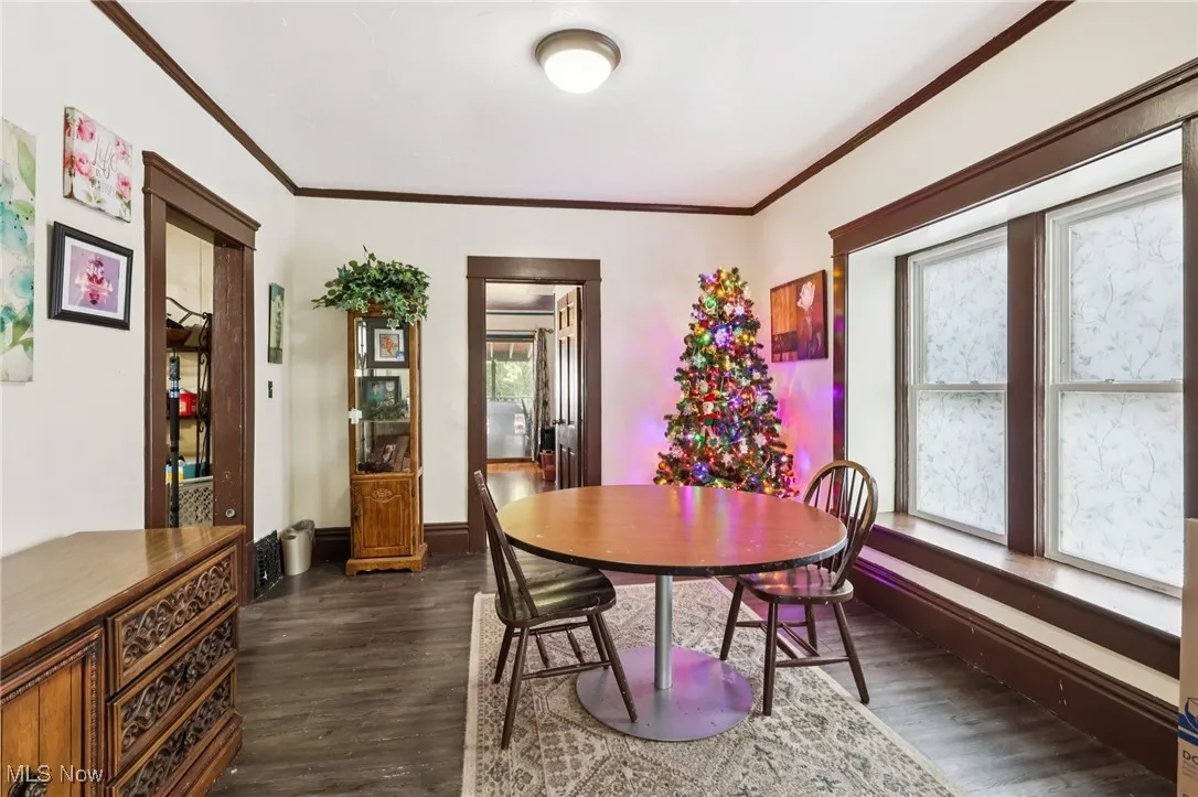 Dining area featuring crown molding and dark wood-style floors