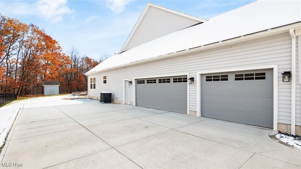 View of side of property featuring a shed and concrete driveway