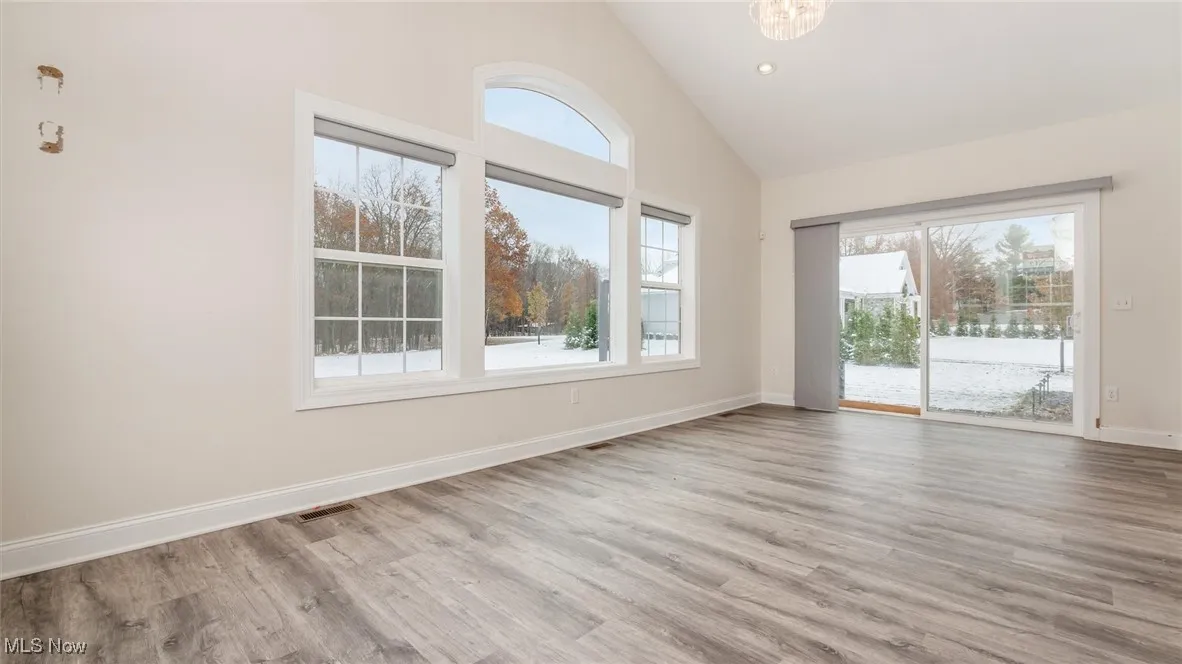 Empty room with high vaulted ceiling, wood finished floors, and recessed lighting