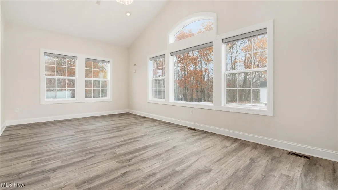 Spare room featuring light wood-style flooring, recessed lighting, and high vaulted ceiling