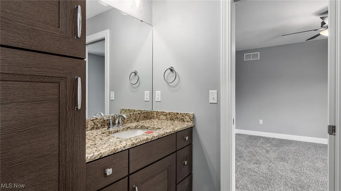 Bathroom featuring vanity, carpet, and a ceiling fan