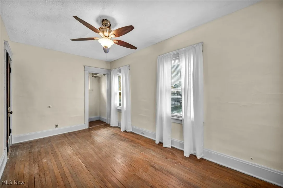 Unfurnished bedroom featuring hardwood / wood-style flooring, ceiling fan, and a textured ceiling