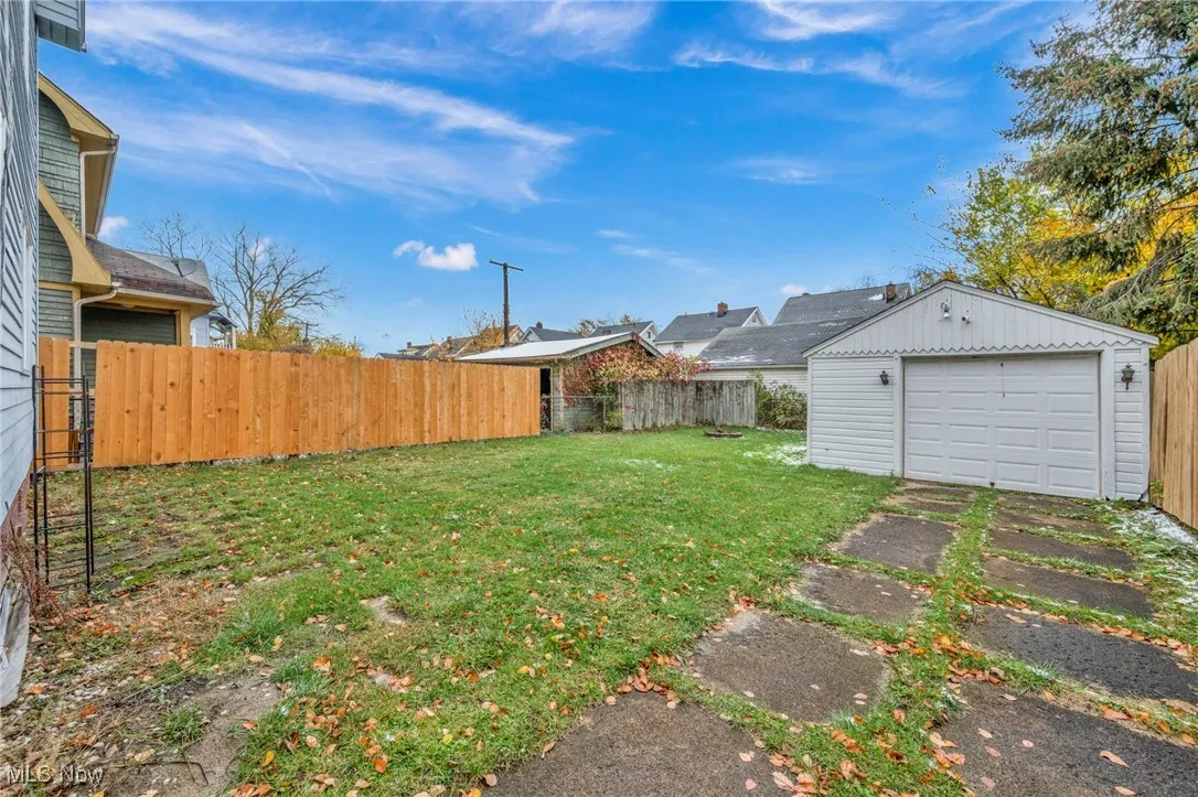 Fenced backyard featuring an outdoor structure and a garage